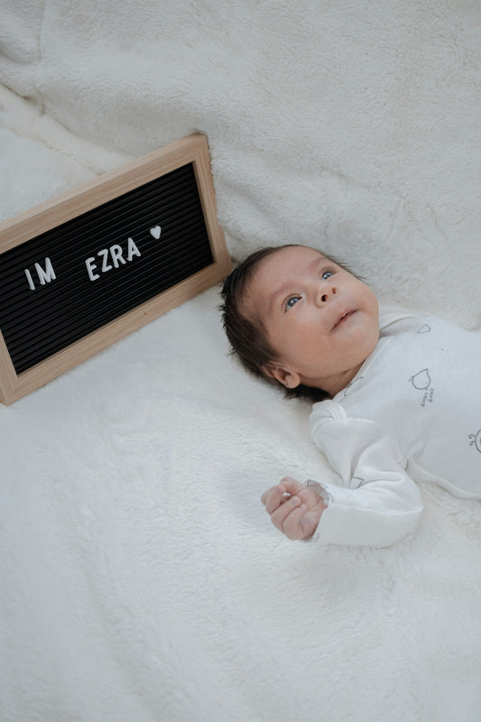 a baby laying on a blanket next to a sign